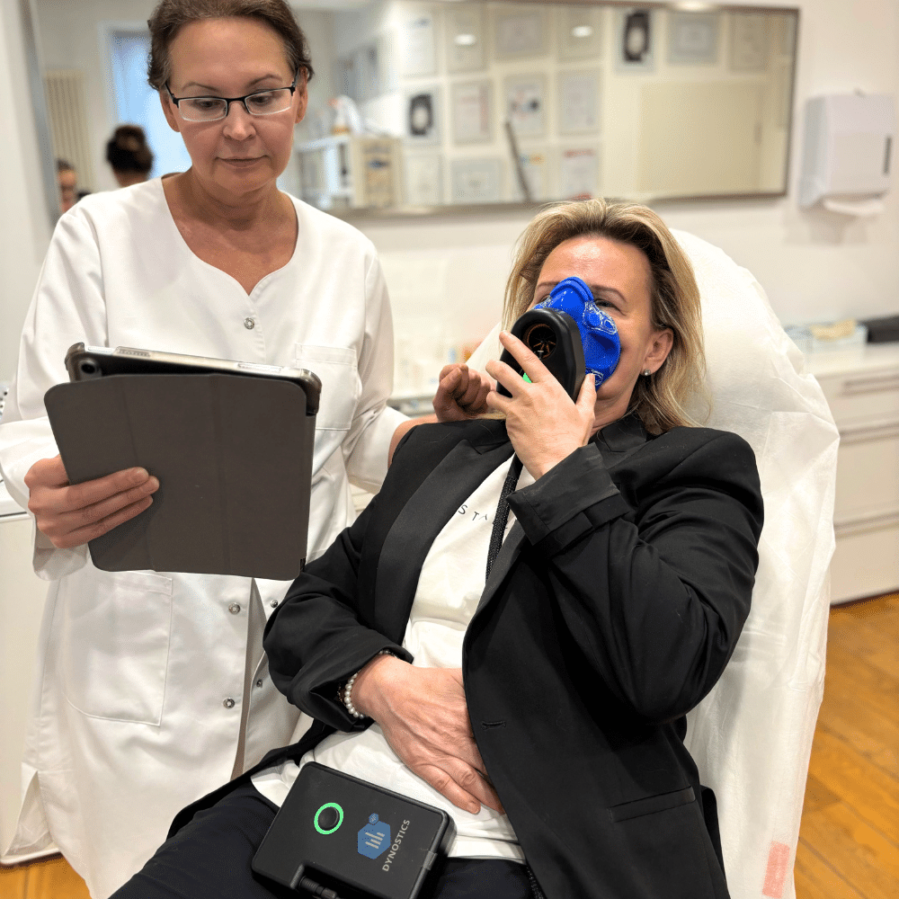 Dr. med. Natalie Wiesen mit Tablet neben einer Patientin, die bei der Stoffwechselanalyse in die Atemmaske atmet – Praxis in Hillesheim (Eifel)