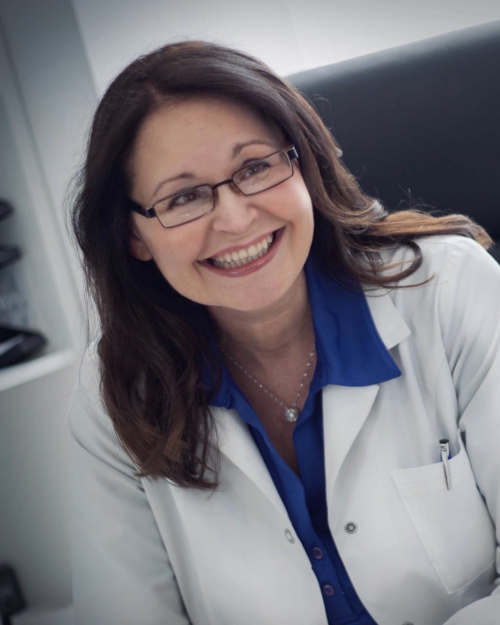 Dr. med. Natalie Wiesen im weißen Kittel am Schreibtisch ihrer Praxis in Hillesheim