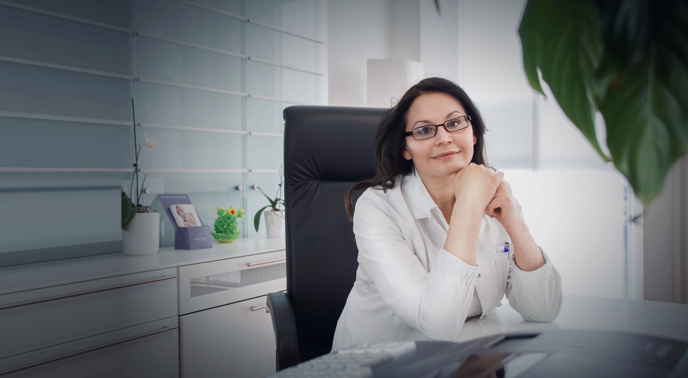 Dr. med. Natalie Wiesen im weißen Kittel am Schreibtisch ihrer Privatpraxis in Hillesheim, Eifel